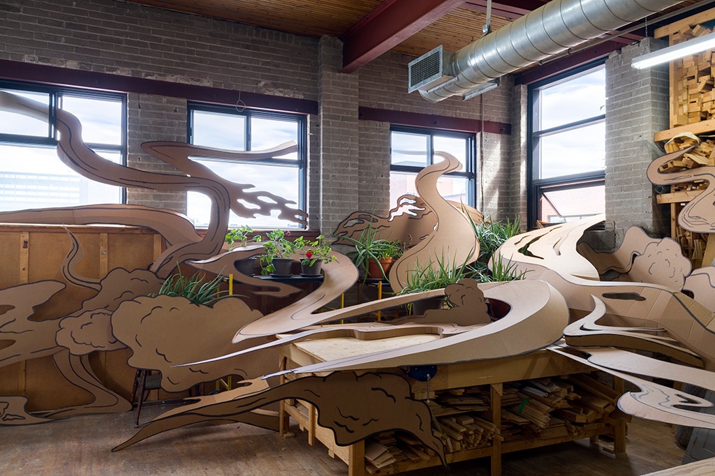 An indoor art installation consisting of swirling organic shapes and foliage that resembles a serene Japanese garden.